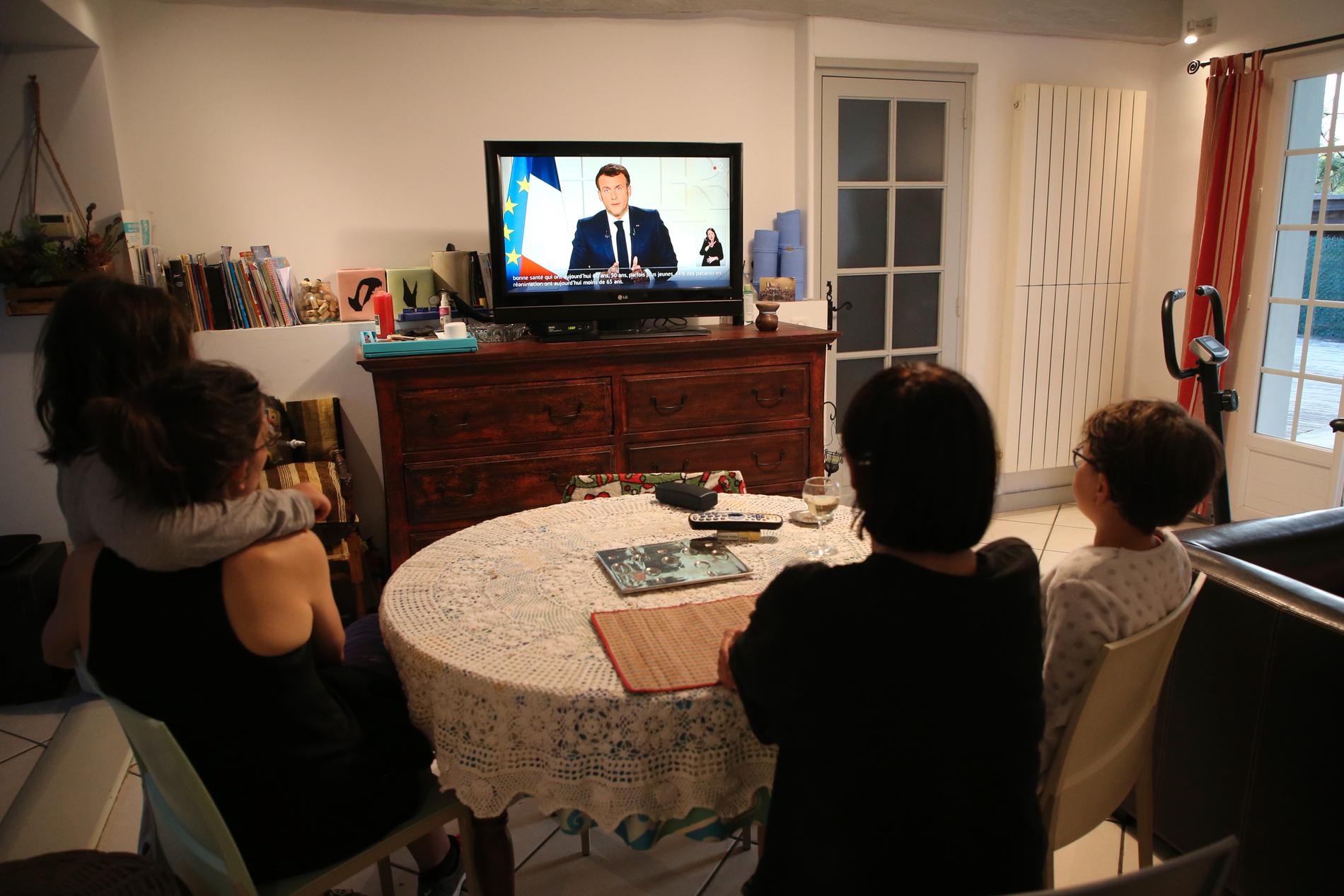 En familj lyssnar till Emmanuel Macrons tal.