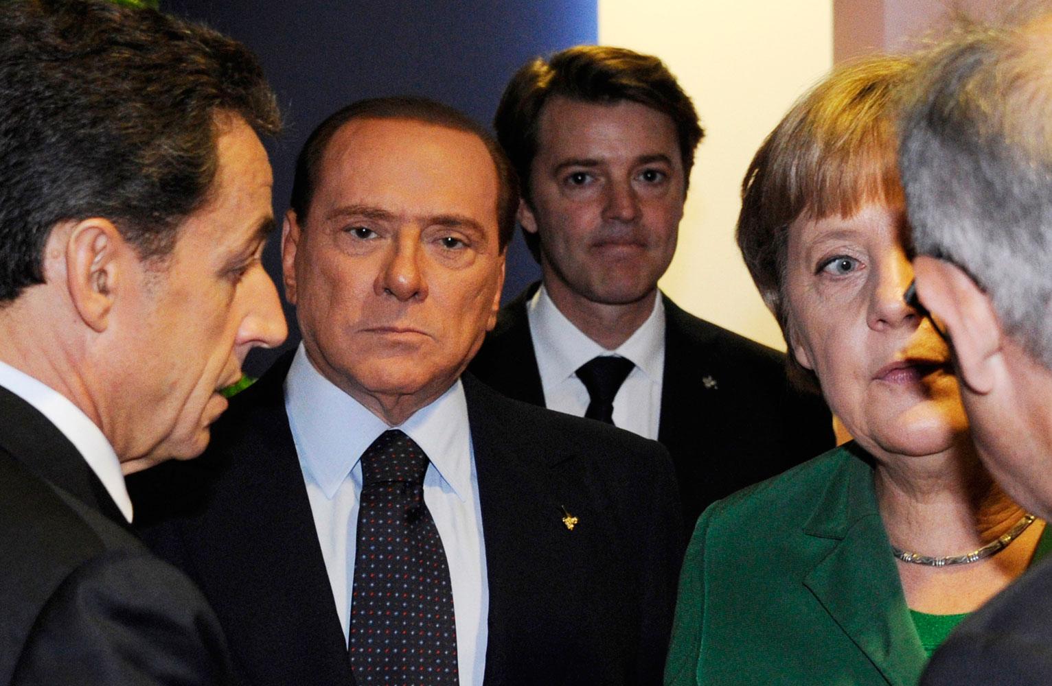 En sammanbiten Silvio Berlusconi mellan Sarkozy och Merkel.