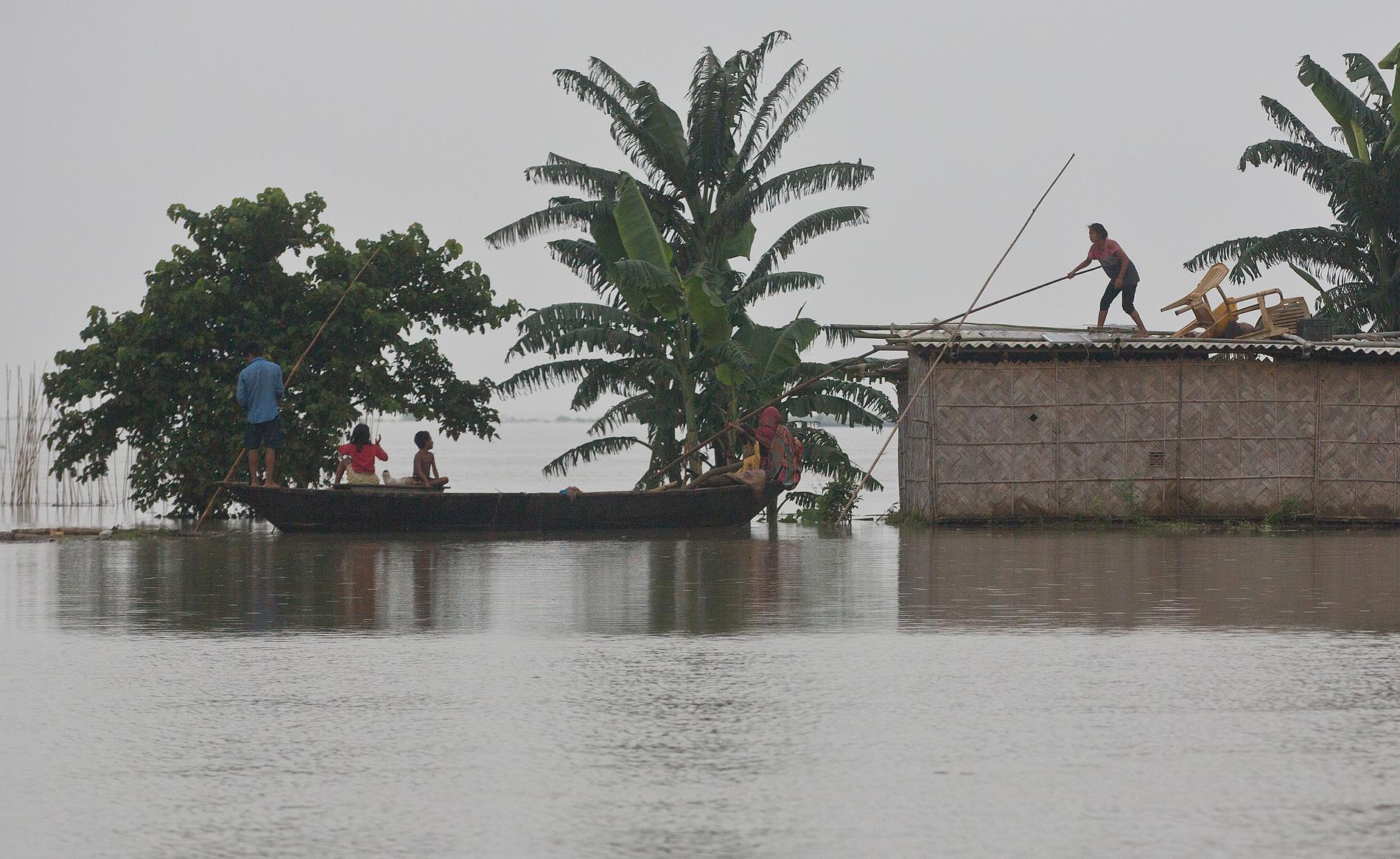 En flicka i Indien som står på ett hustak får hjälp att komma ombord på en båt.