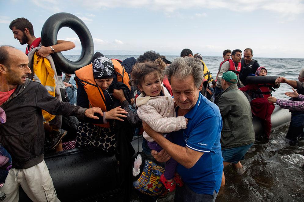 Flyktingar från en ranglig flotte kommer till Lesbos.