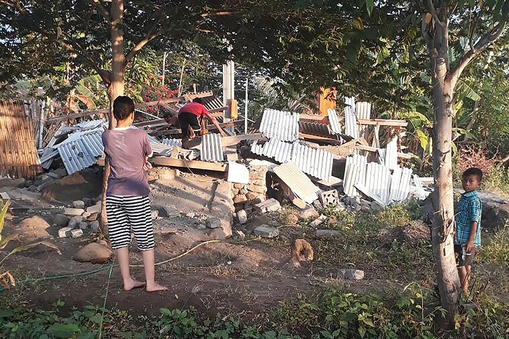 Bild från Nusa Tenggara Barat Disaster Mitigation Agency (BPBD) visar flera personer vid ett förstört hus. 