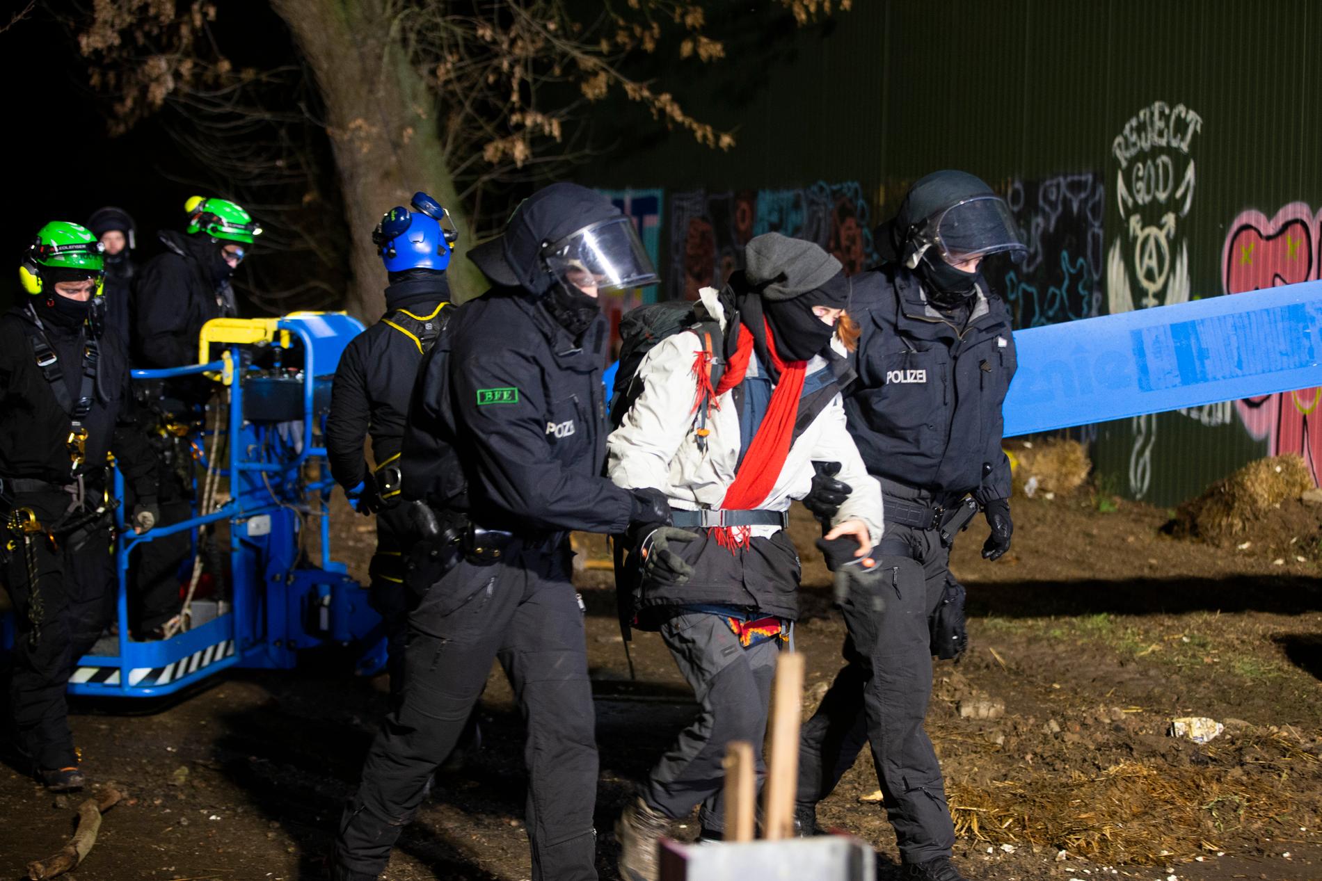 Poliser för bort en klimataktivist från den ockuperade brunkolsbyn Lützerath.