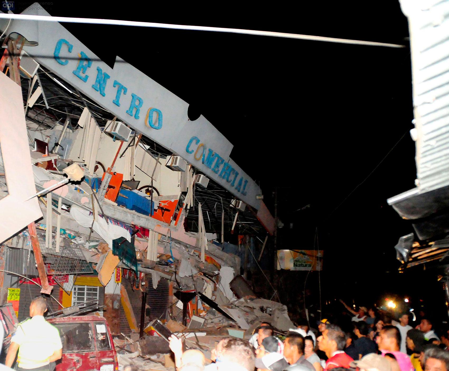 Räddningsarbetare jobbar med att hjälpa överlevande ut ur en kollapsad byggnad i staden Manta.