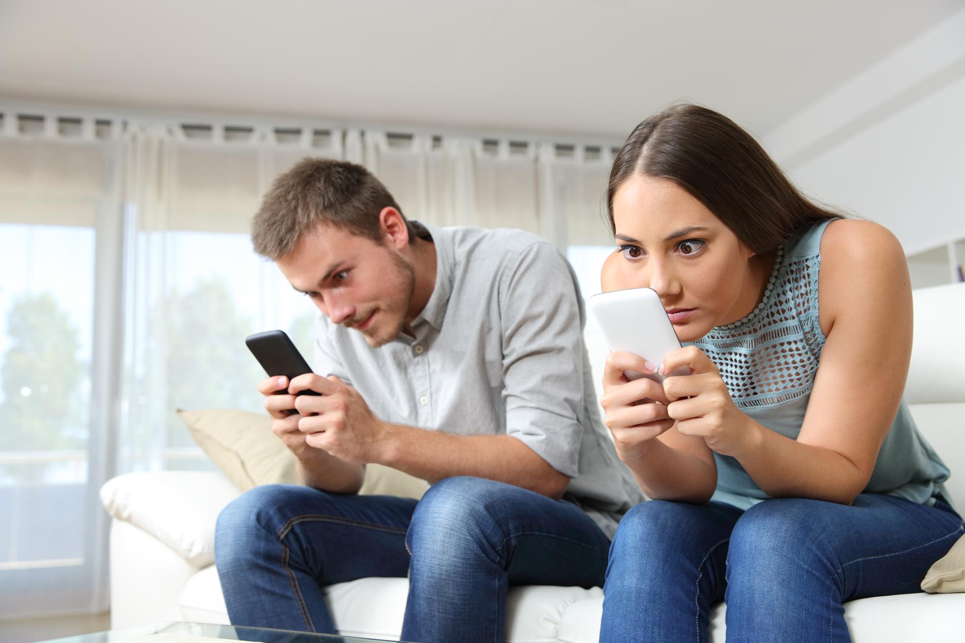 Två unga personer sitter klistrade vid sina mobiler.