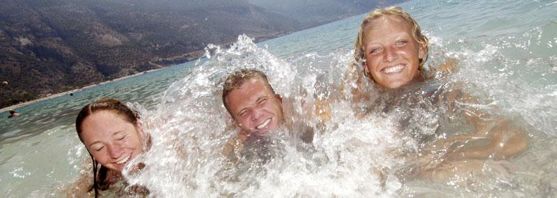 Tre glada polacker badar vid stranden i Öludeniz.