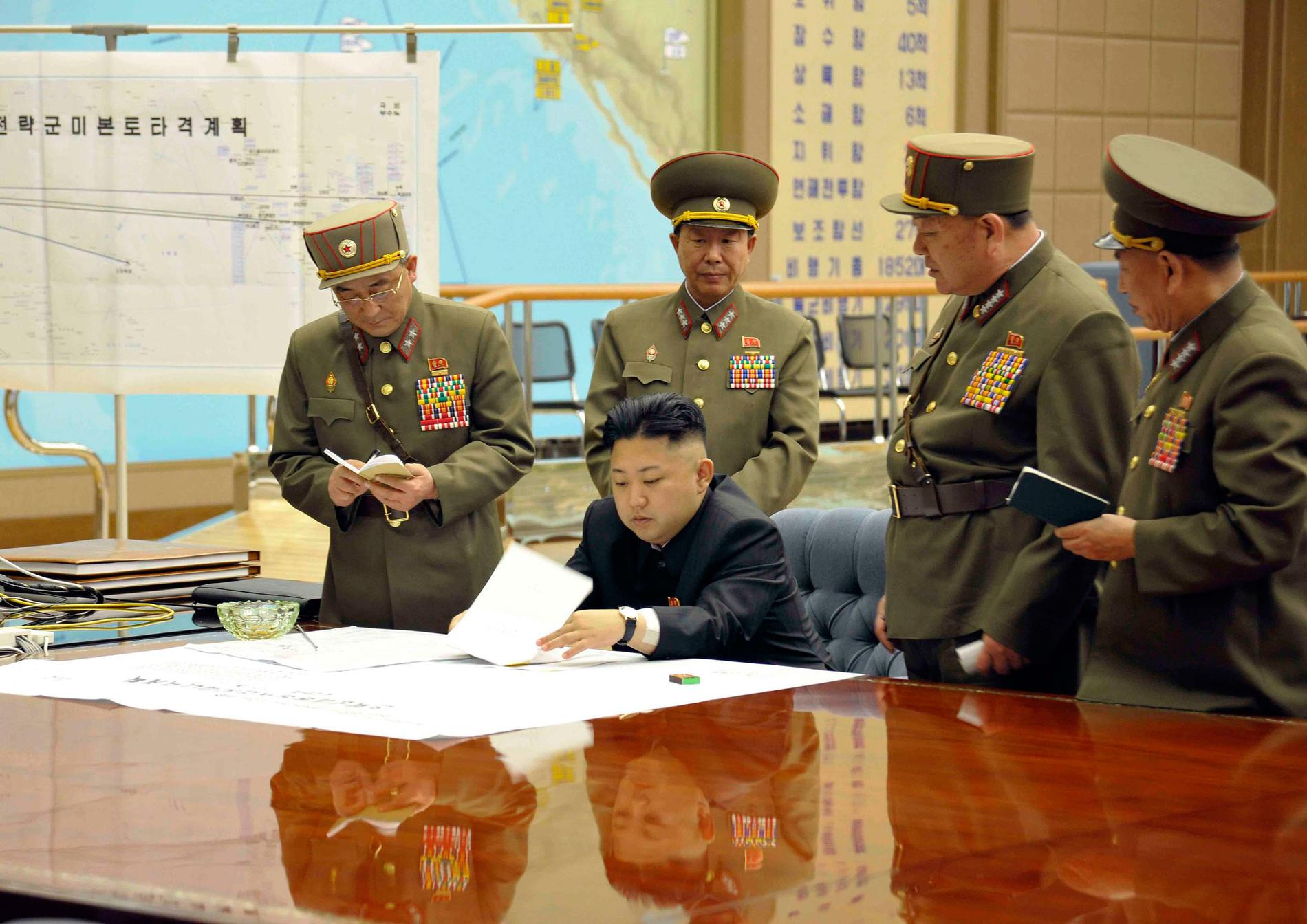 Kim Jong-Un med höga militärer. I bakgrunden syns kartan där flera amerikanska städer är utmärkta som mål.