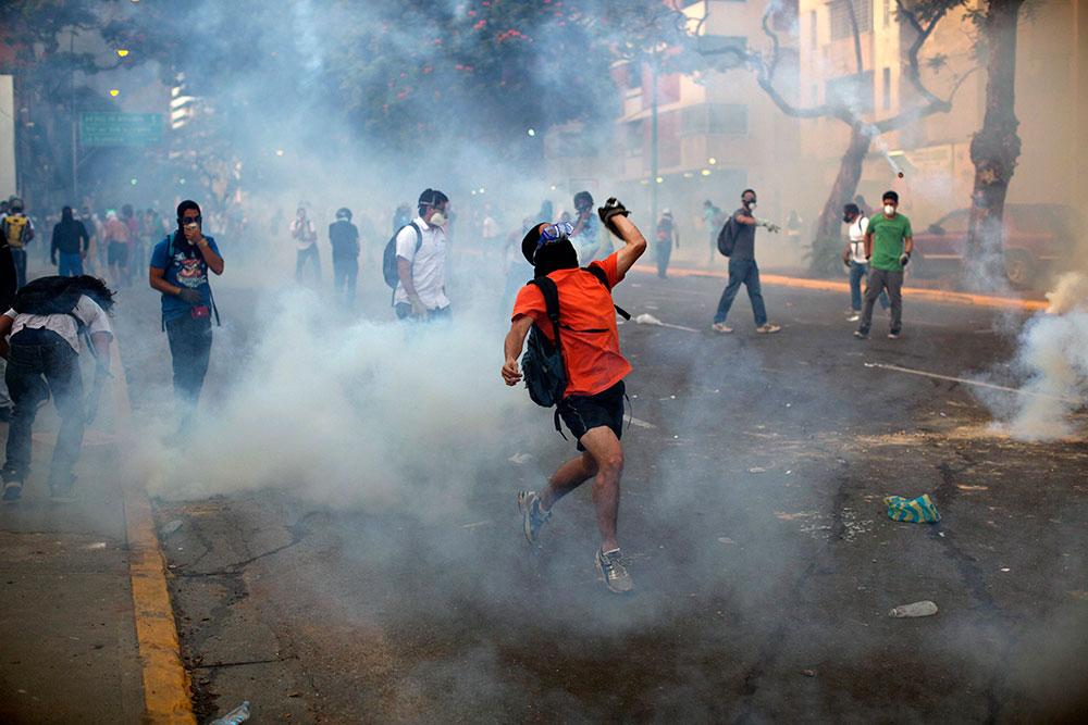 Tårgas Demonstranter i Caracas kastar sten och möts av tårgas från säkerhetsstyrkor.