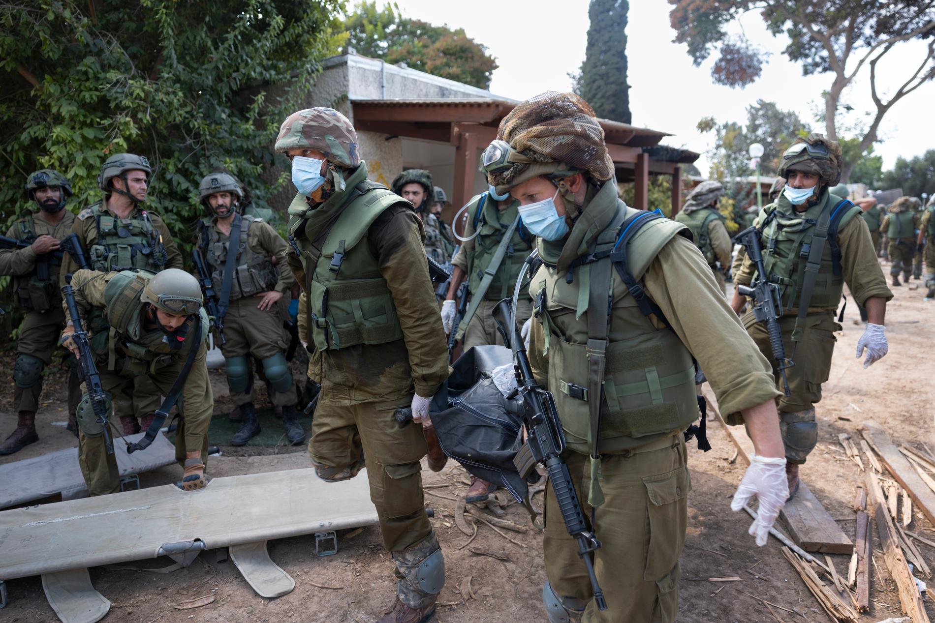 Soldater i Kfar Aza i Israel bär ut dödsoffer. 