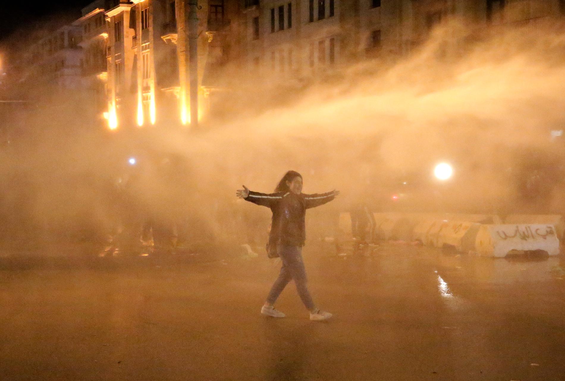 En demonstrant sprejas av vattenkanoner i helgens protester i Beirut.