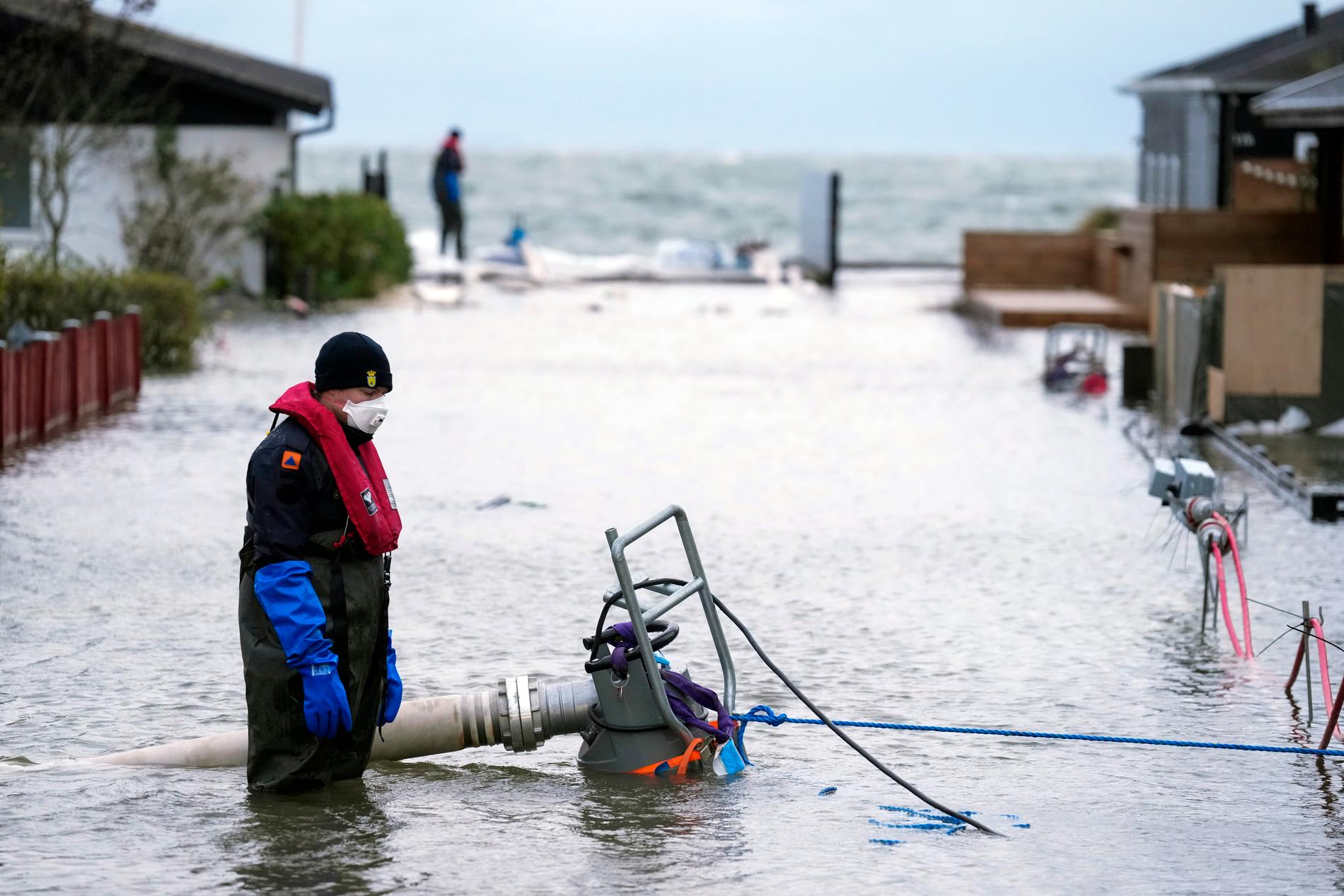 En invånare i danska Haderslev på Jylland försöker pumpa bort vatten som har översvämmat hans kvarter, den 20 oktober i år. Stormväder hade då fört med sig stora mängder regn. Arkivbild.