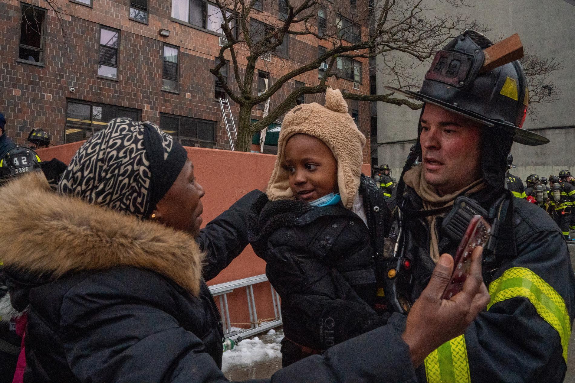 En brandman har räddat ett barn som han lämnar över till sin mamma.