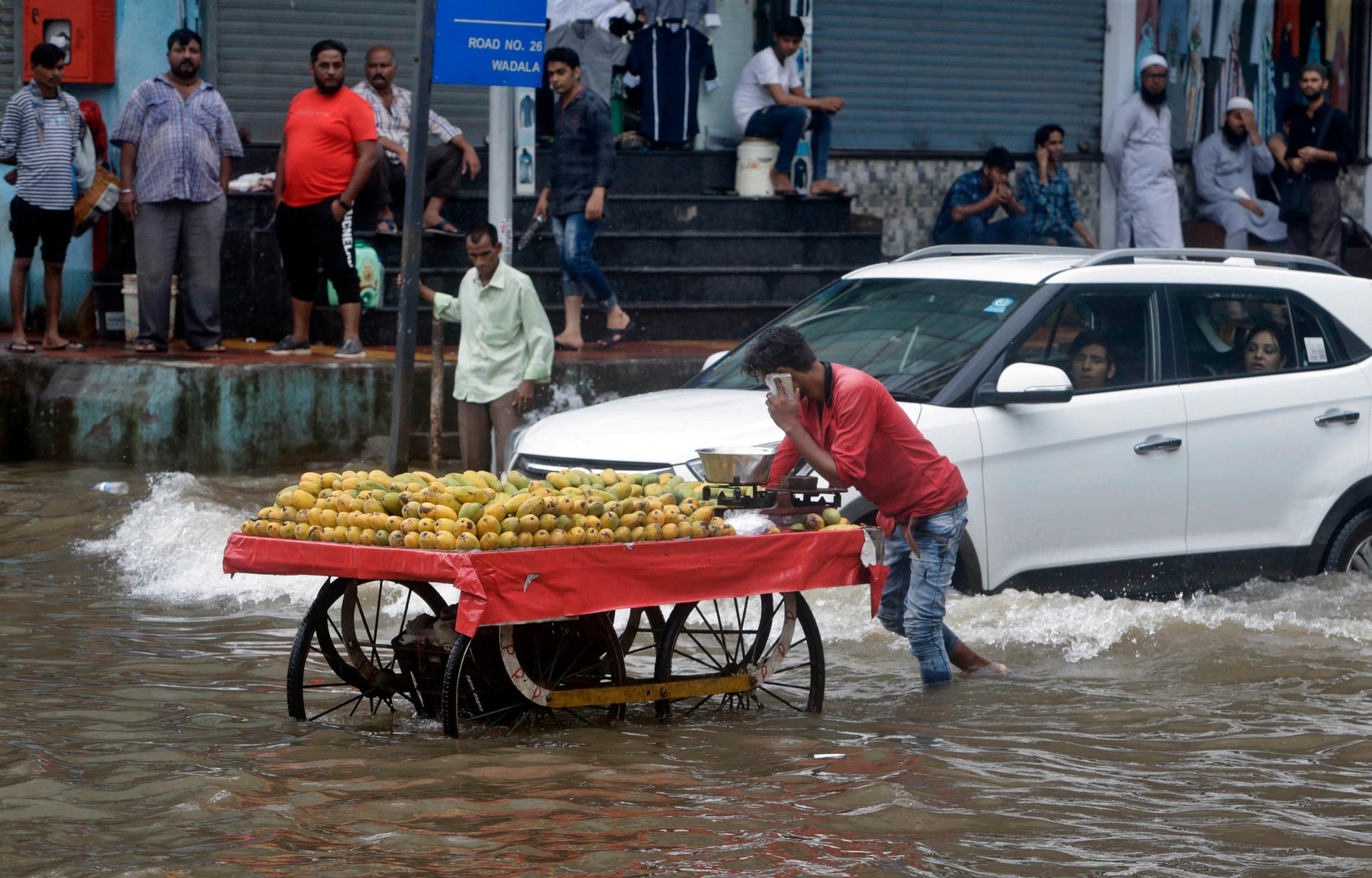En fruktförsäljare drar sin vagn längs en vattenfylld gata i Bombay i Indien i början av juli. Monsunregnen har orsakat omfattande översvämningar i Indien.