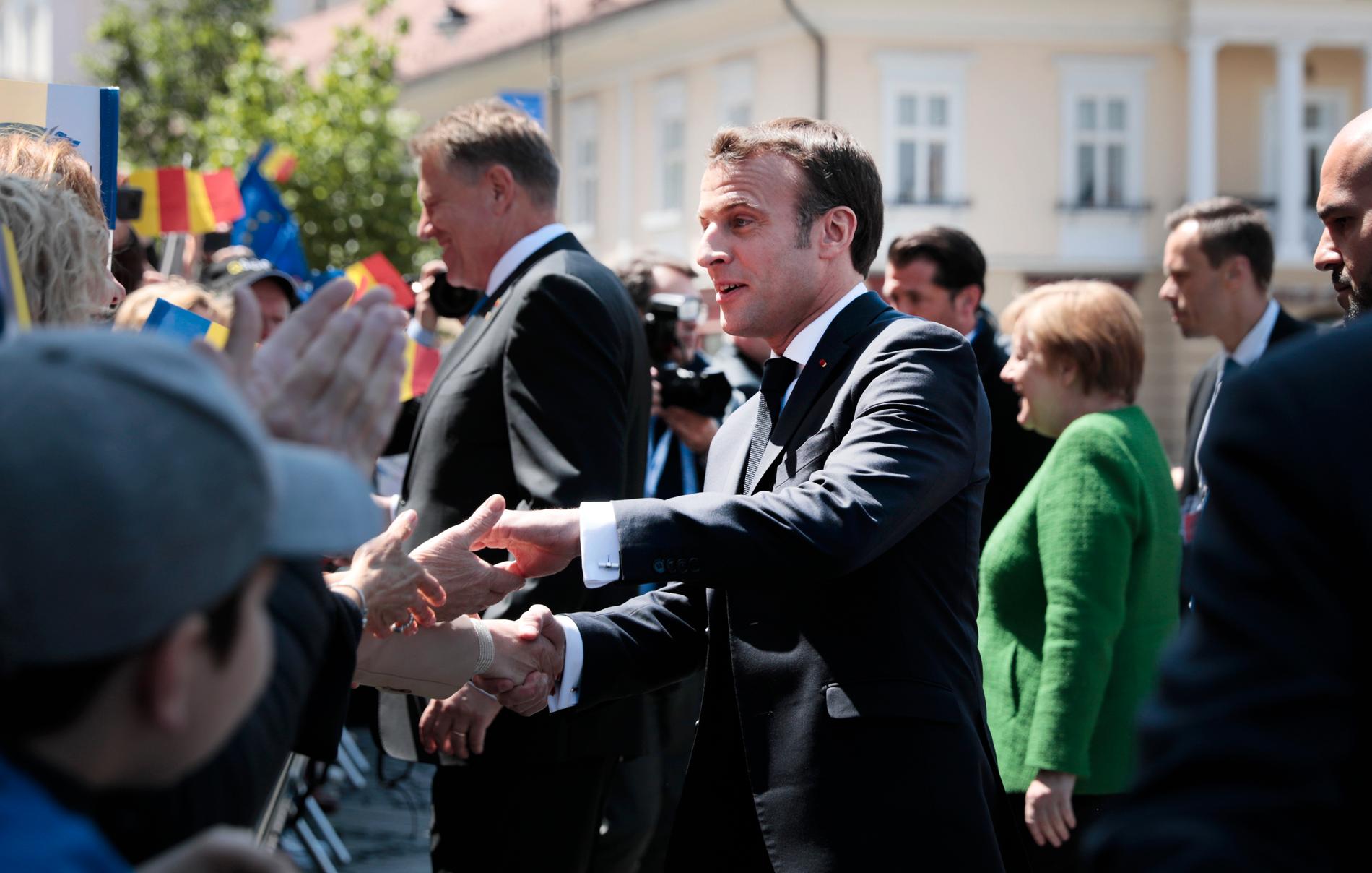 Frankrikes president Emmanuel Macron hälsar på åskådarna utanför toppmötet i Sibiu.