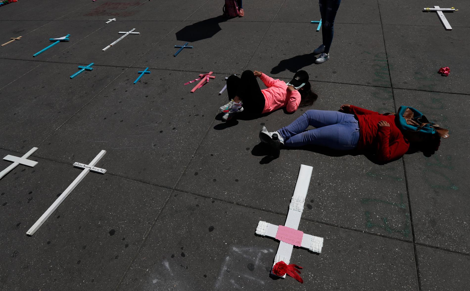 Kvinnor ligger sida vid sida med kors till minne av mordoffer under en demonstration i Mexico City i mars.