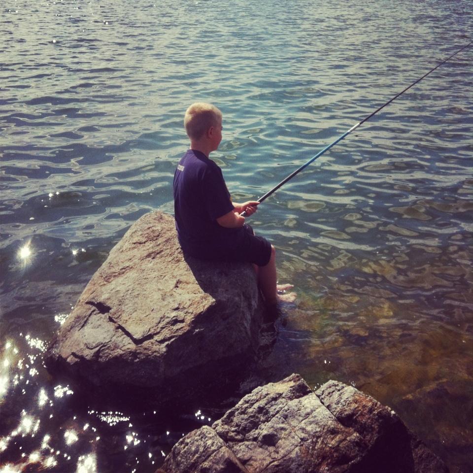 Kasper, 8 år, metar och svalkar fötterna i Hallsfjärden.
