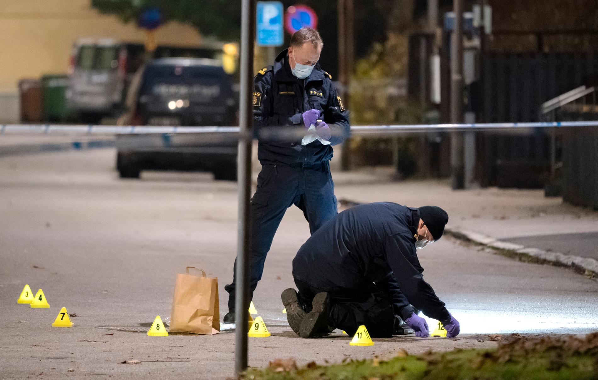 Polisens kriminaltekniker tar hand om en tomhylsa innanför avspärrningarna efter skottlossningen.