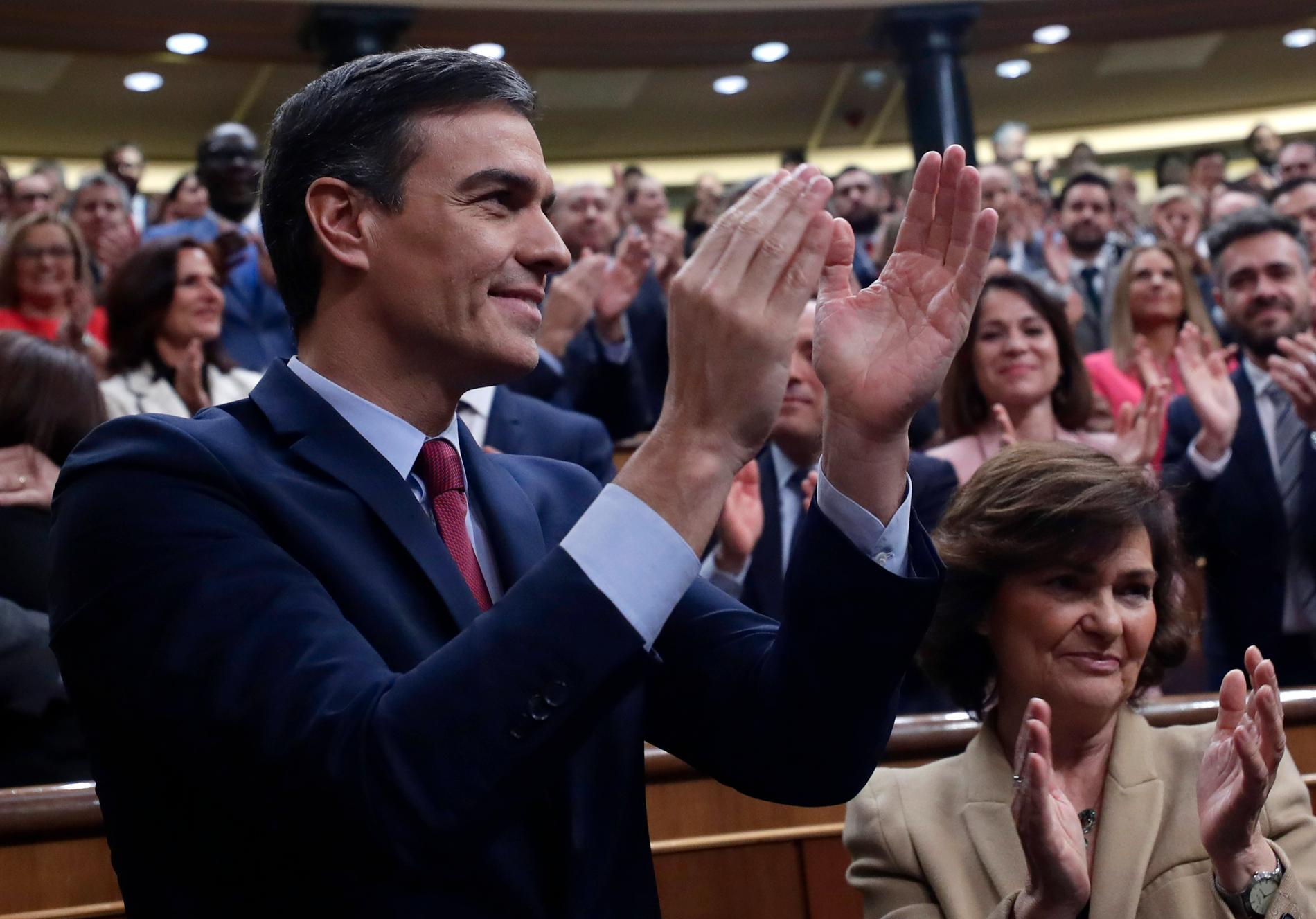 Socialdemokraten Pedro Sánchez applåderar ihop med sina partikamrater efter att med knapp marginal ha säkrat posten som premiärminister.