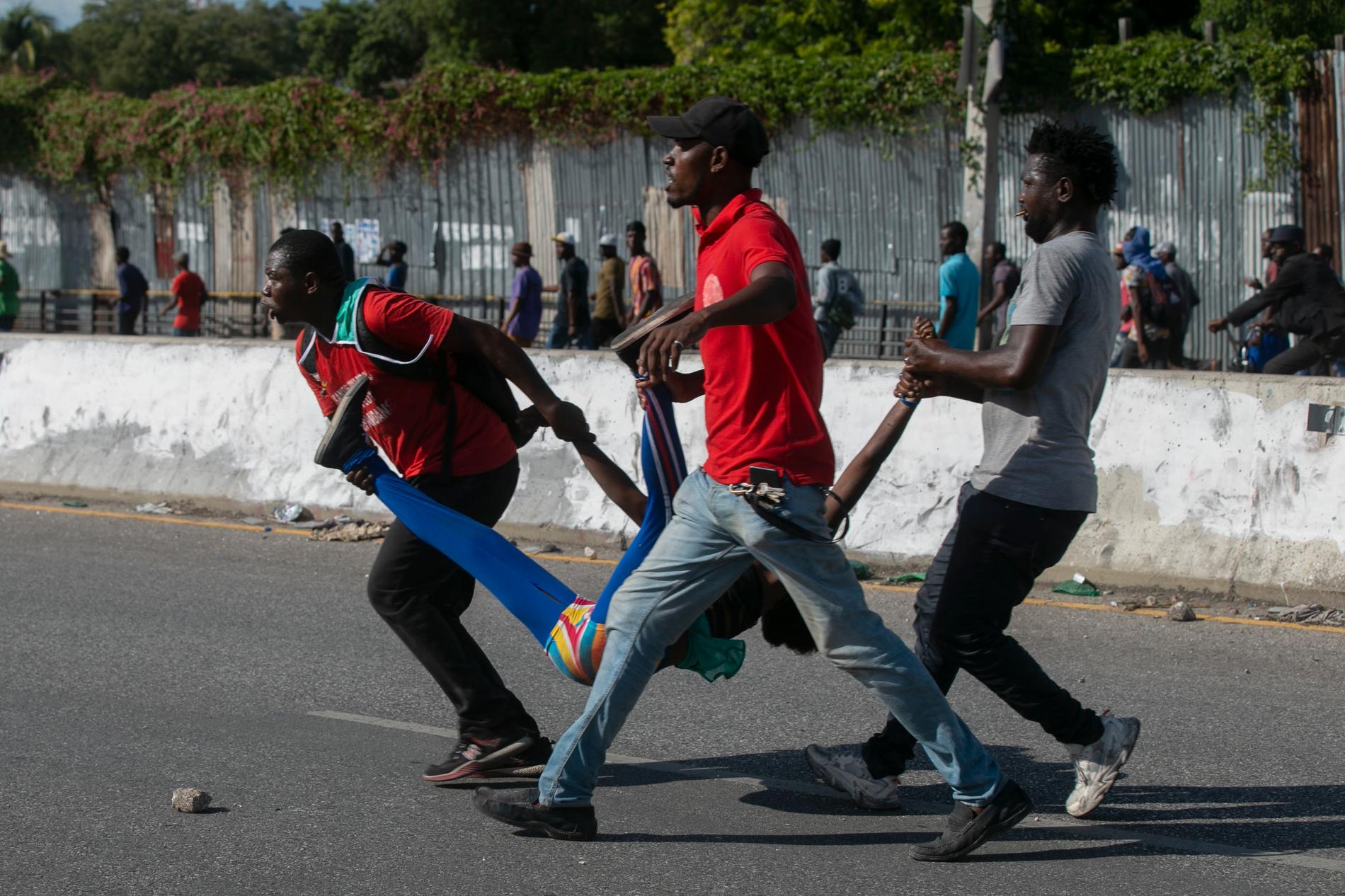 En kvinna som skjutits av polis bärs iväg i Haitis huvudstad Port-au-Prince den 10 oktober.