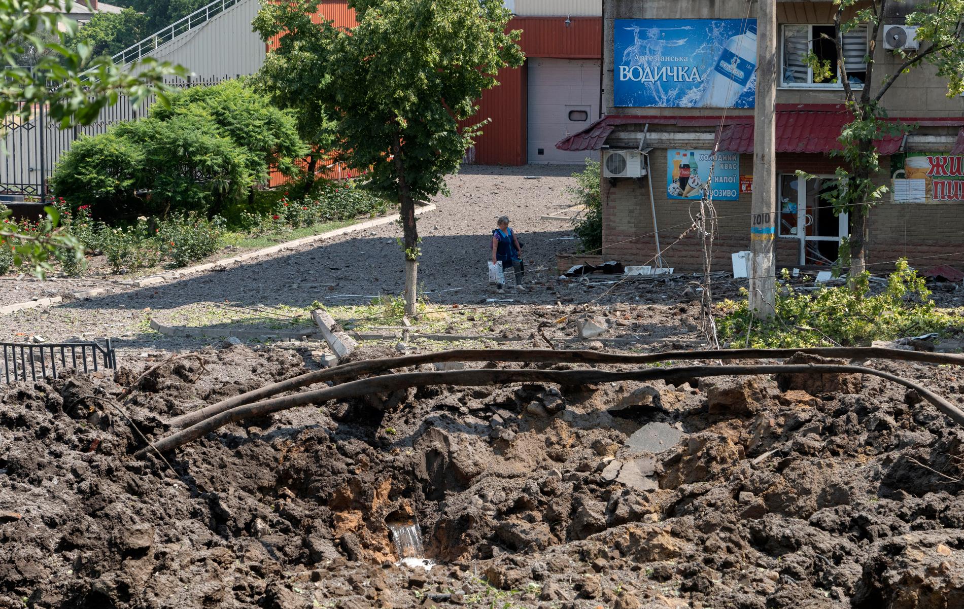 En kvinna i staden Bachmut i Donetskregionen tittar på kratern som orsakats av en rysk raket. Bild från 1 juli.