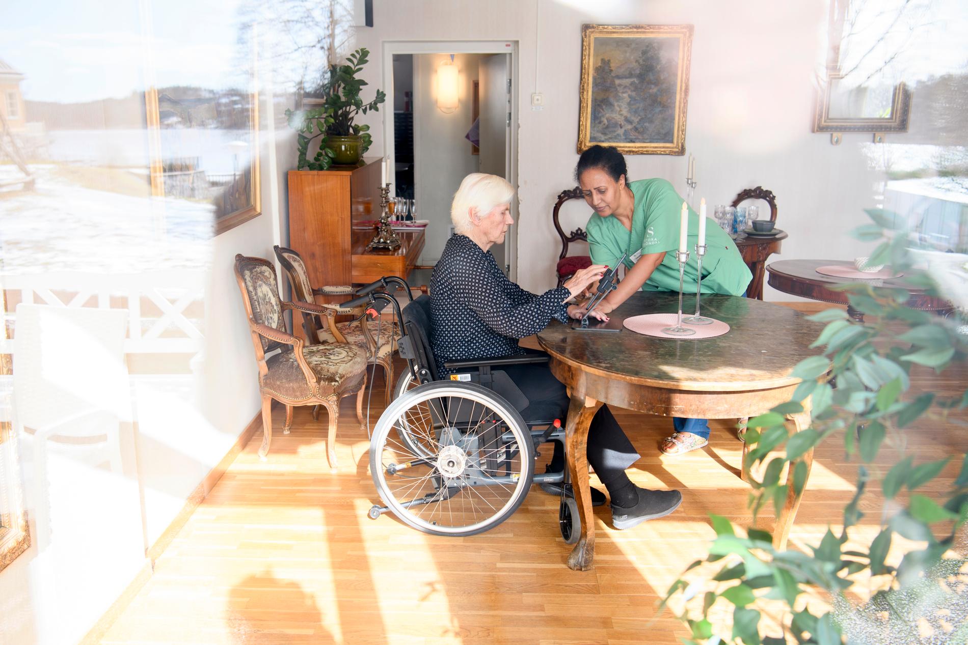 Brita Öhman på äldreboendet Kyrkbyn i Stora Sköndal får hjälp av Yordanos Teklezghi med att komma i gång med ett videosamtal.
