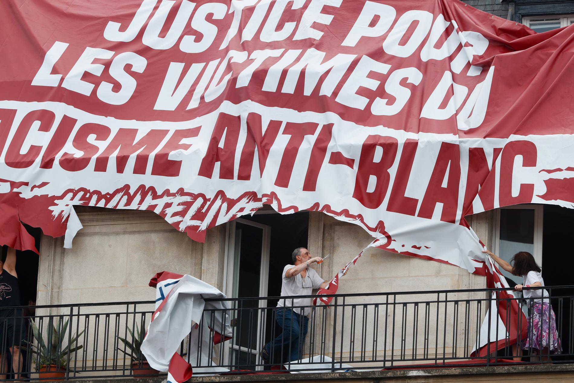 Boende river sönder en främlingsfientlig banderoll i Paris.