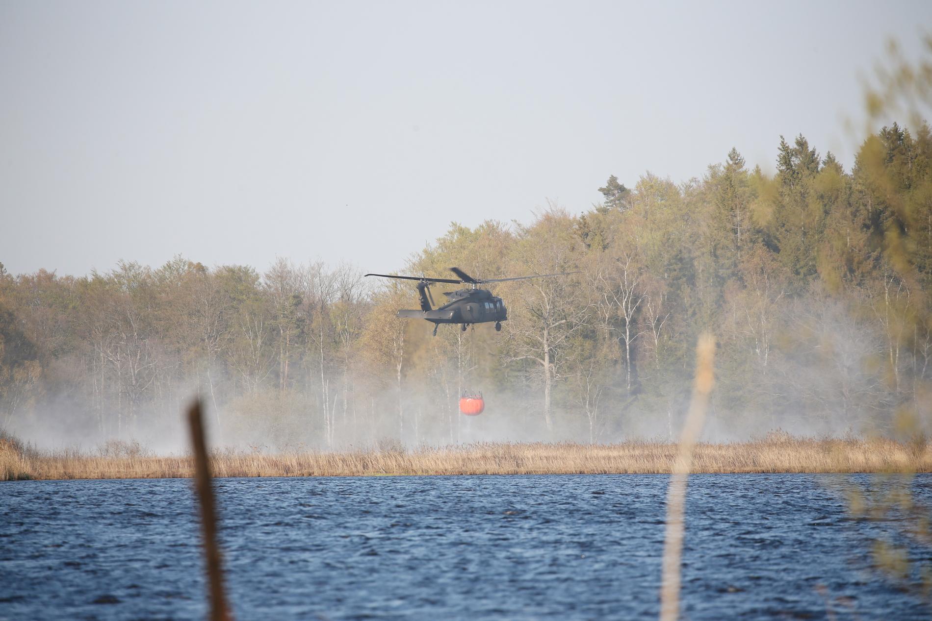 En helikopter hämtar vatten i sjö för att vattenbomba i Hästveda. 