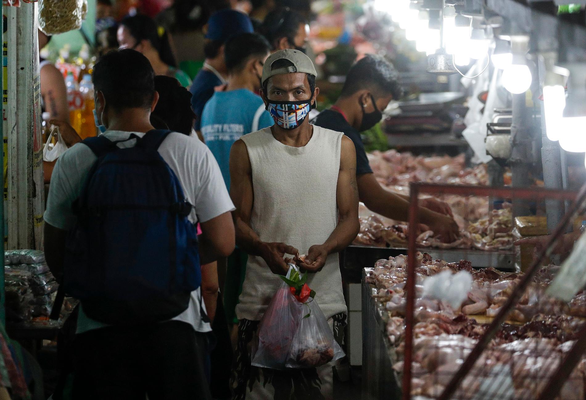 En man bär ansiktsmask på marknaden. Megastäder som filippinska Manila, där människor bor tätt och fattigdomen är utbredd, är en tacksam grogrund för smittspridning.