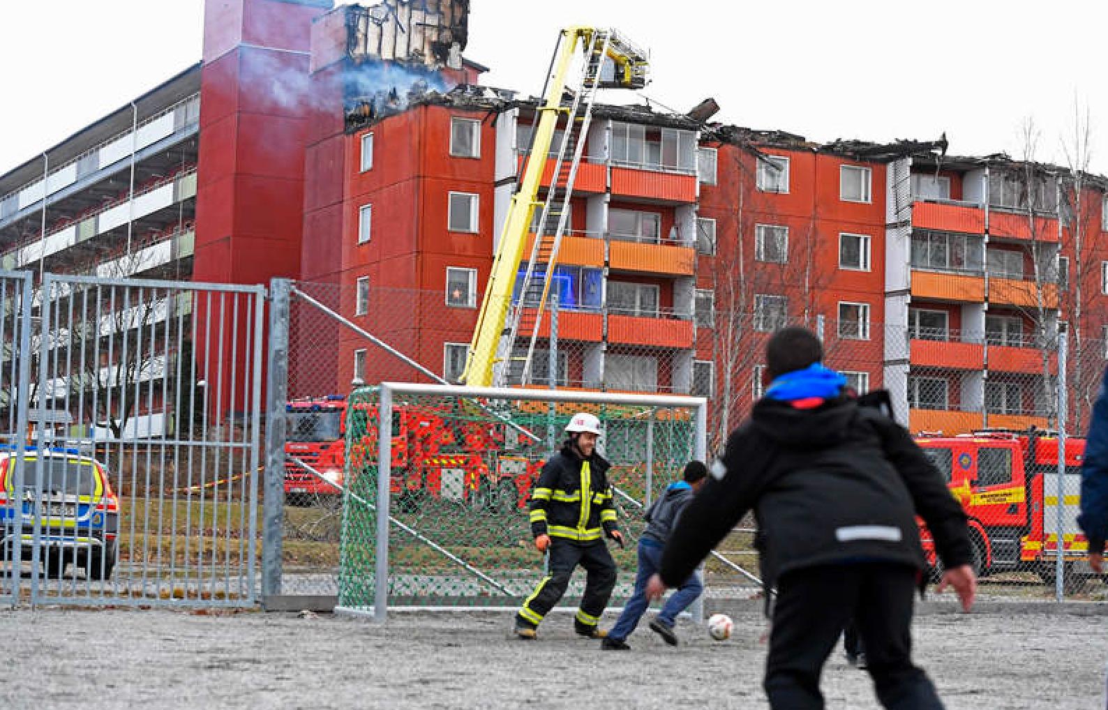 Här spelar en av brandmännen fotboll med barnen i Husby.