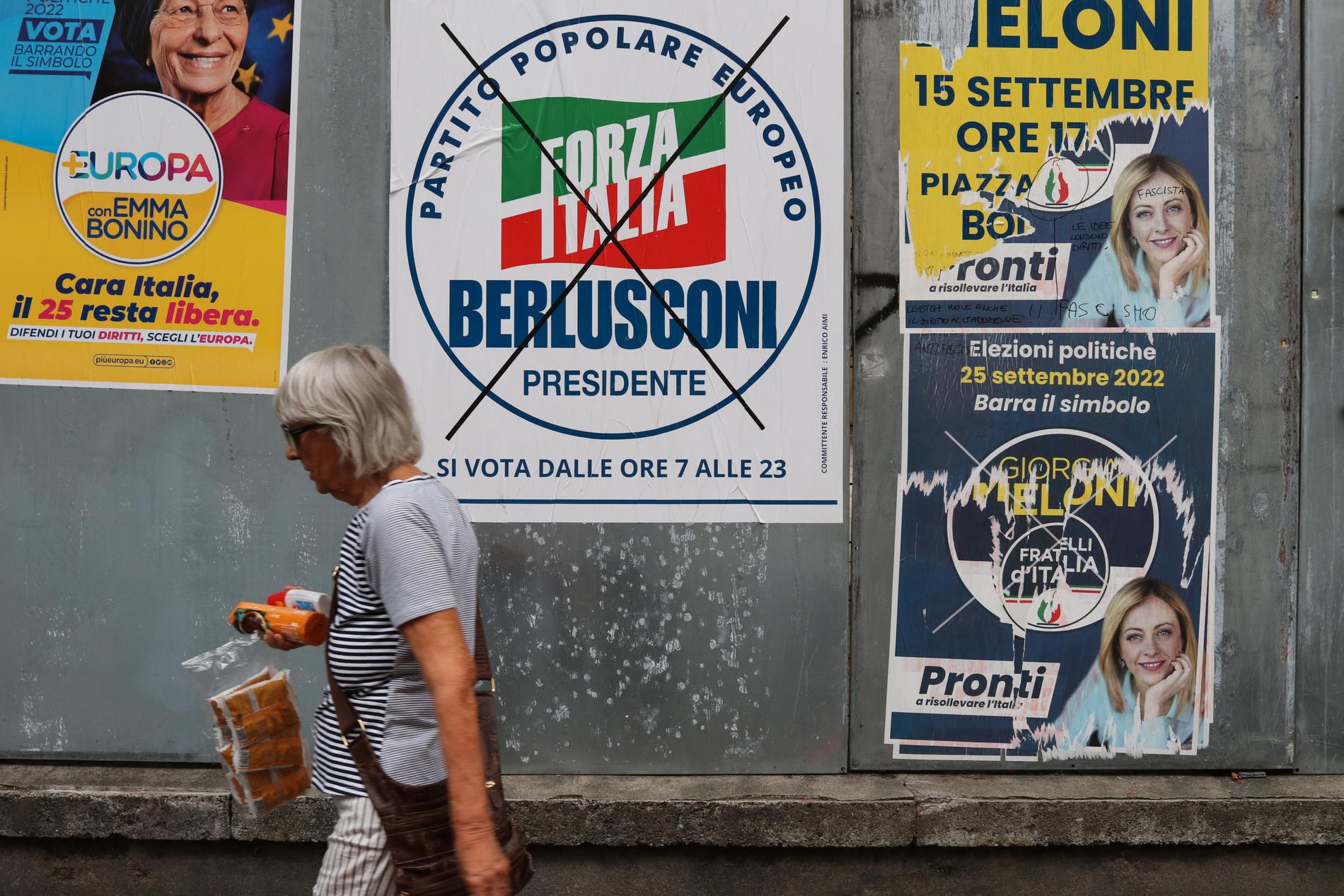 "Dårar! De är alla dårar", ropar en kvinna som går förbi en vägg med valaffischer inför valet i Italien den 25 september.