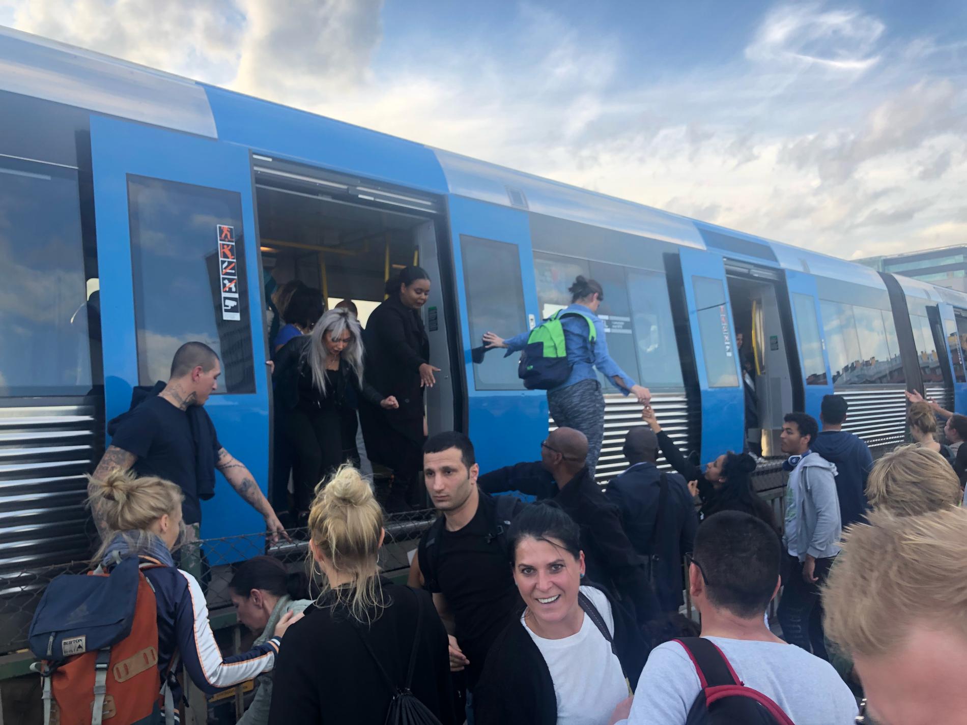 Resenärer evakueras från stillastående tåg.