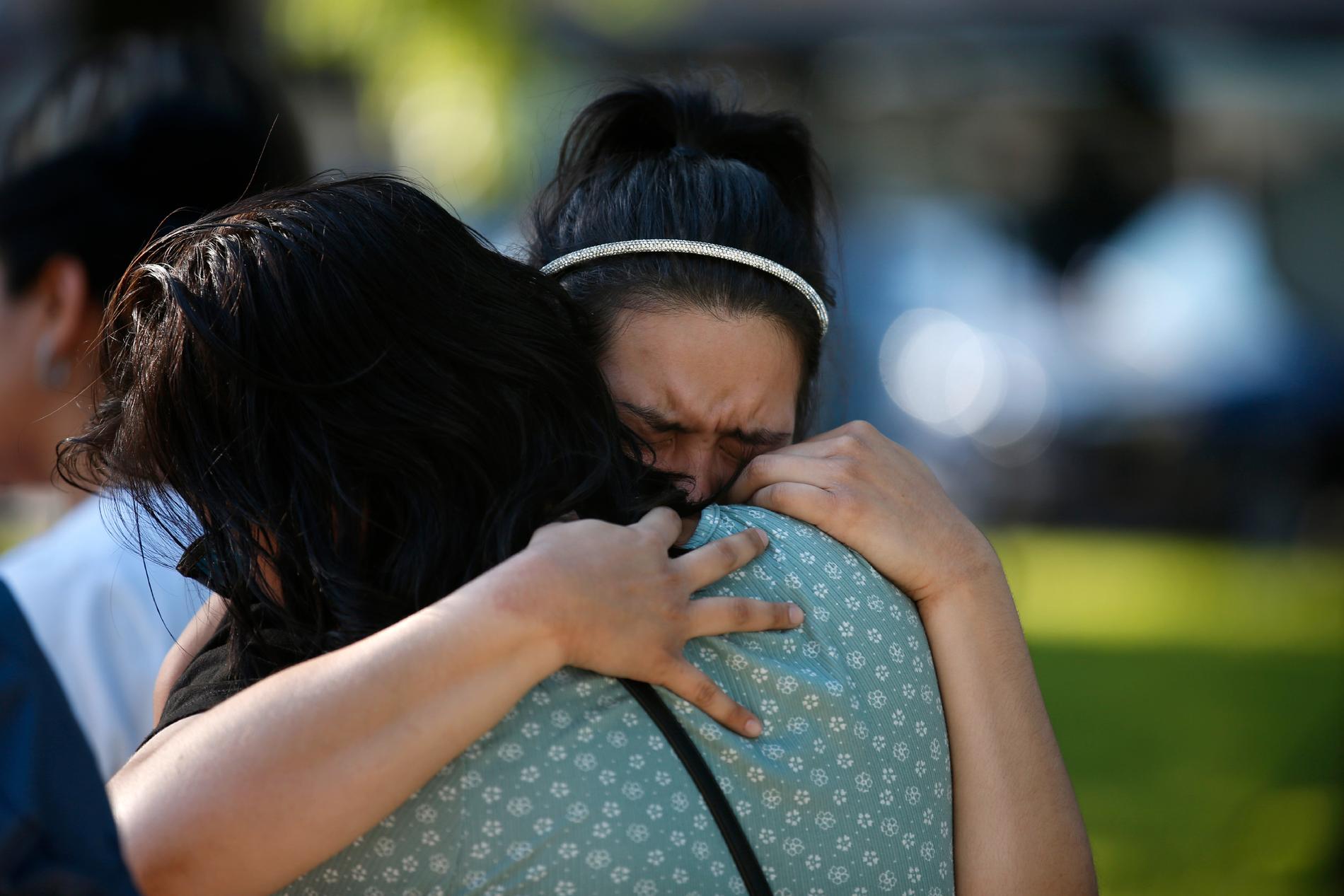 Gråtande människor vid en minnesplats efter skjutningen i skolan i Uvalde i USA.