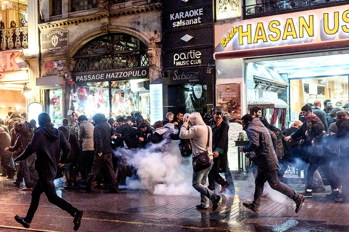 Människor springer undan tårgasattacker från turkisk kravallpolis under en demonstration efter att en kurdisk advokat blev skjuten och dödad i Diyarbakir i Turkiet på lördagen.