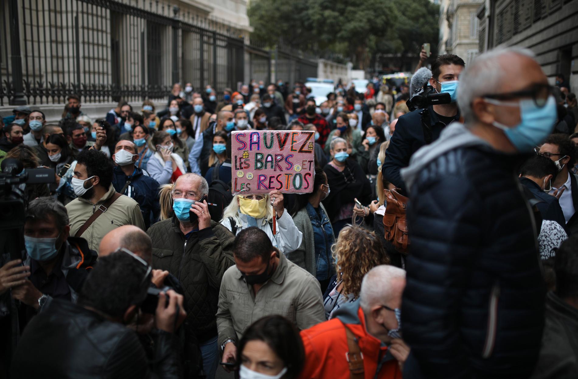 Arga krögare demonstrerade under fredagen i Marseille mot regeringens nya krav på nedstängningar. Här en demonstrant med skylten "Rädda barerna och restaurangerna".