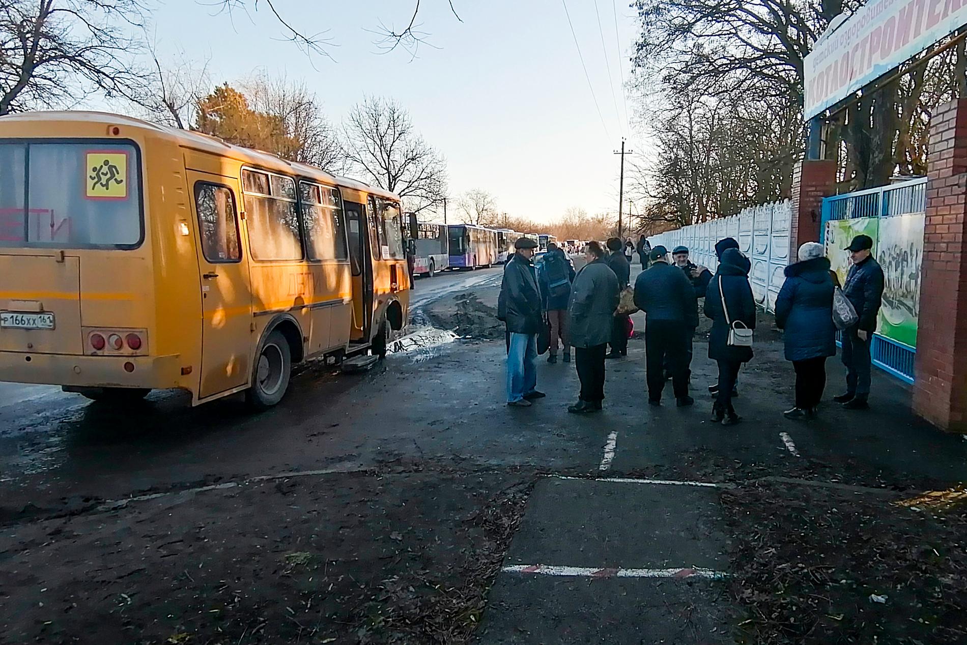 Personer som står vid en buss efter att ha evakuerats från Donetsk under lördagen. 