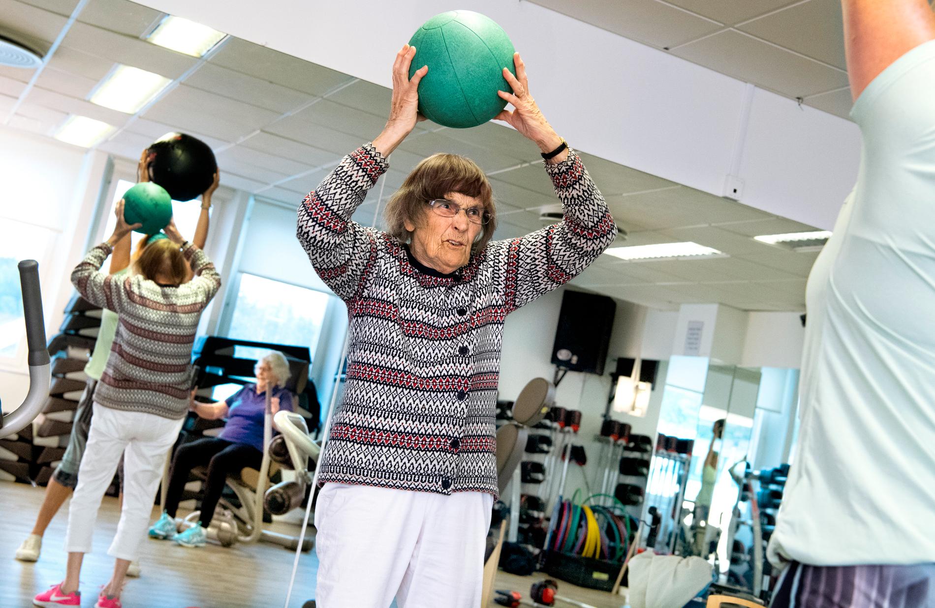 Kerstin Hellgren, 97 år, lyfter upp en medicinboll under cirkelträningen.