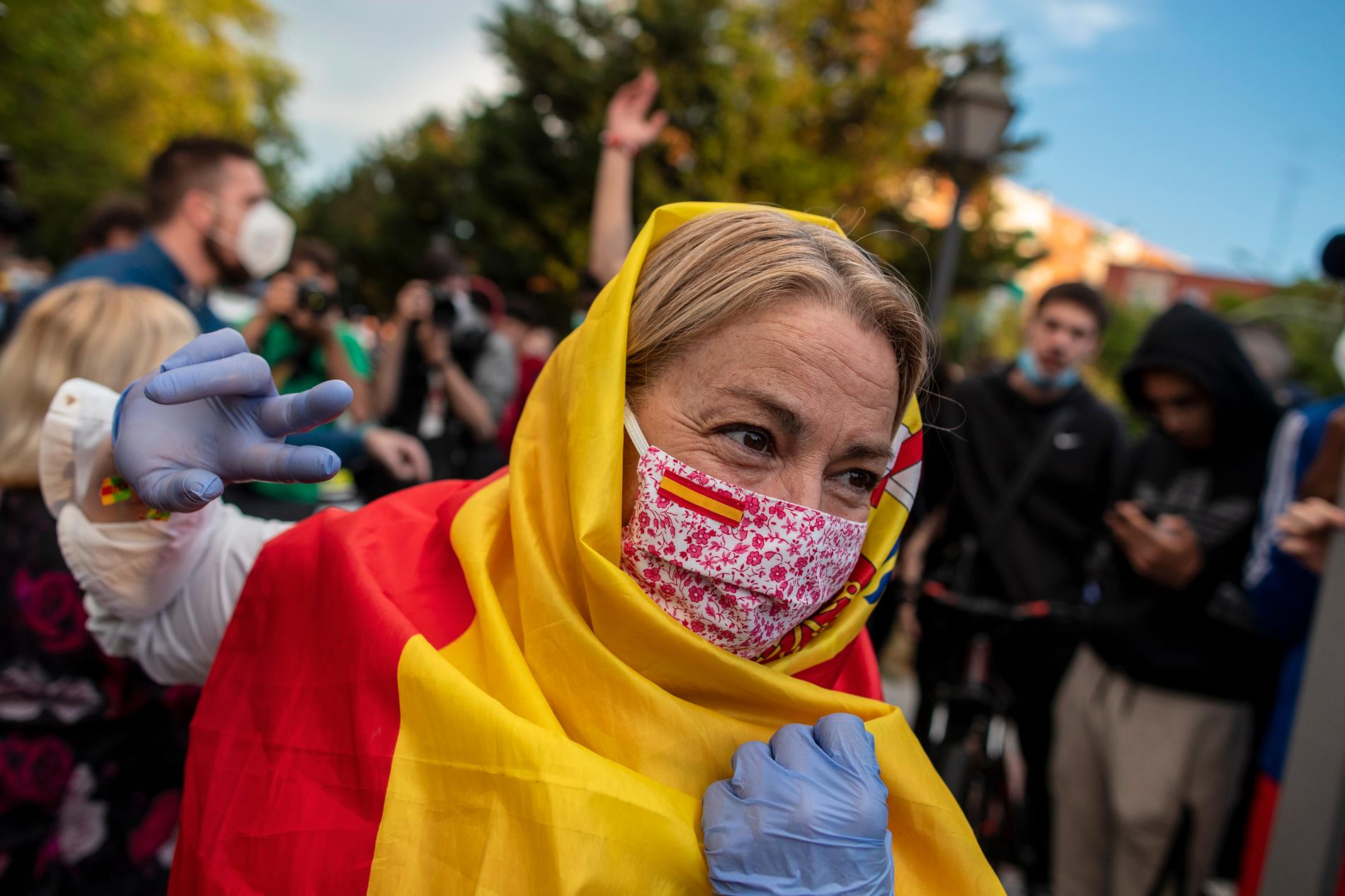 En kvinna draperad i en spansk flagga och med munskydd under en protest mot regeringens hantering av krisen i Alcorcón i tisdags.