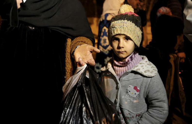 En flicka väntar tillsammans med sin familj att lämna den krisdrabbade staden Madaya i Syrien.