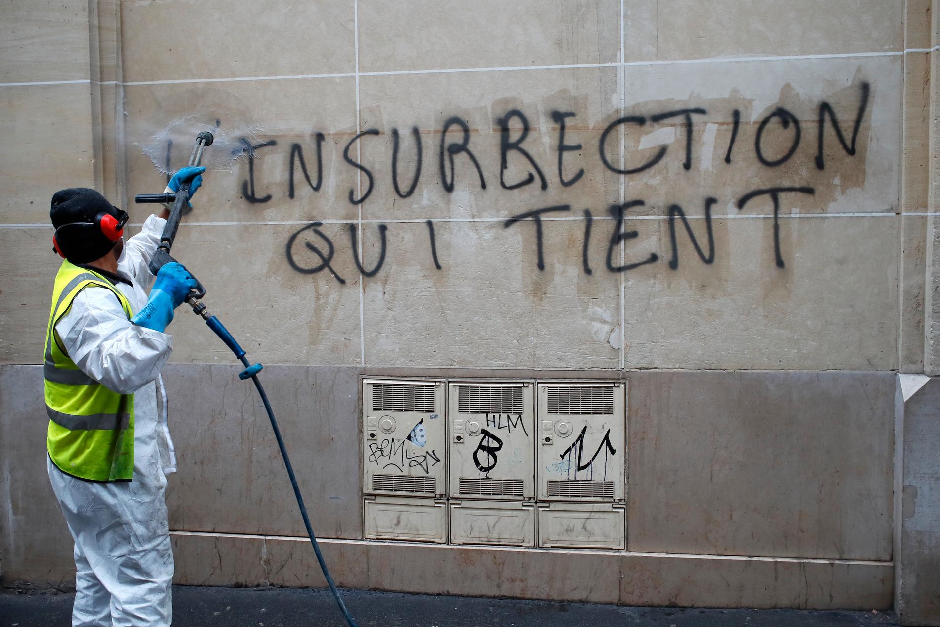Graffiti som kan översättas till ungefär "varaktig revolt" städas bort nära Champs-Elysees.