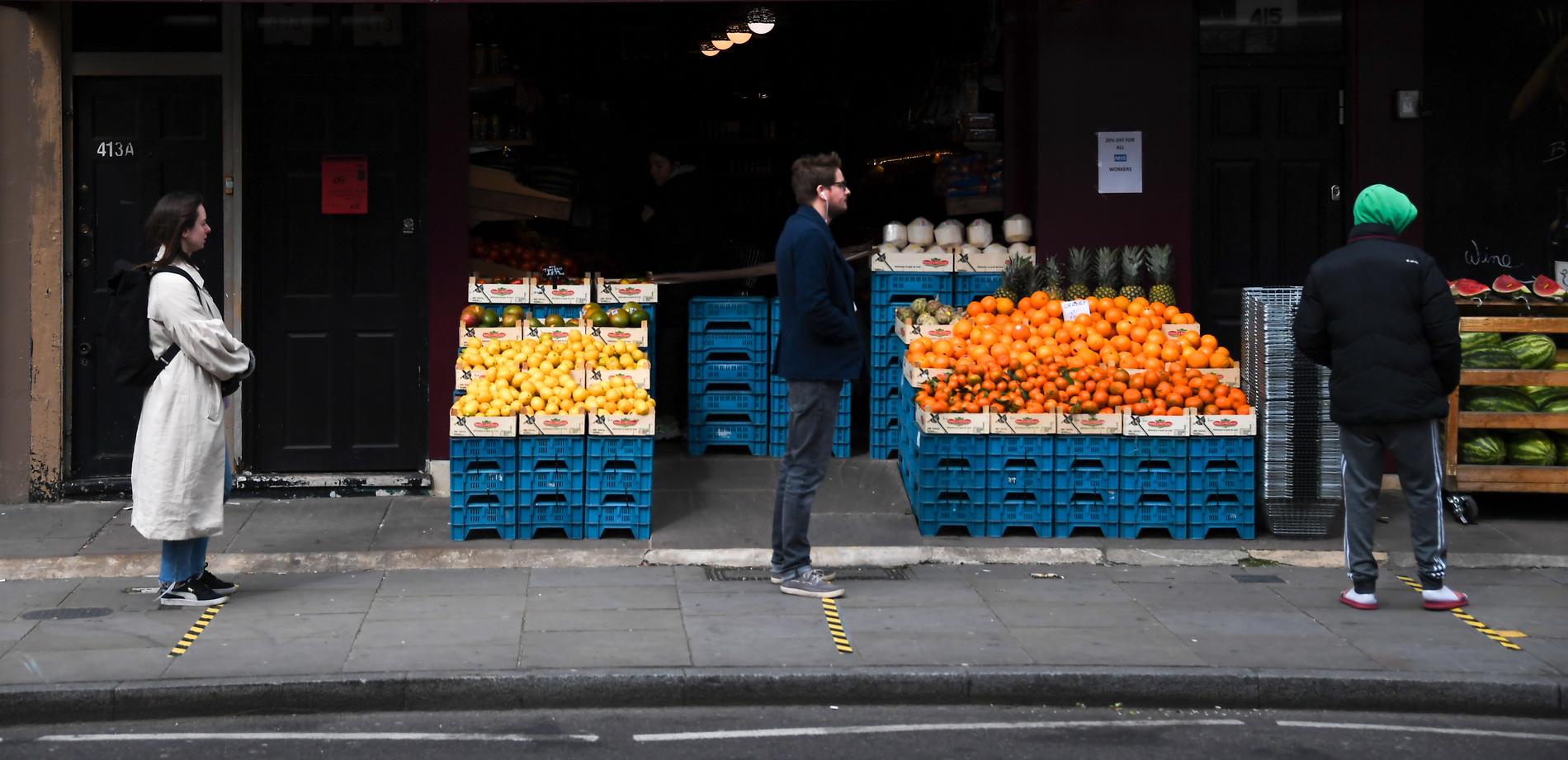 Britterna uppmanas att hålla sig inomhus, men de får gå ut för att köpa mat. Men då ska de hålla två meters avstånd. Här syns folk köa med avstånd utanför en livsmedelsbutik i London.