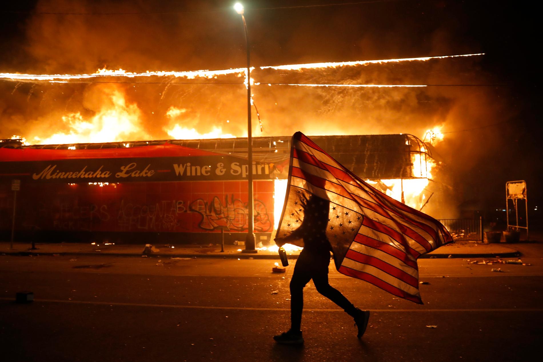 En demonstrant bär den amerikanska flaggan upp och ner under nattens protester. 