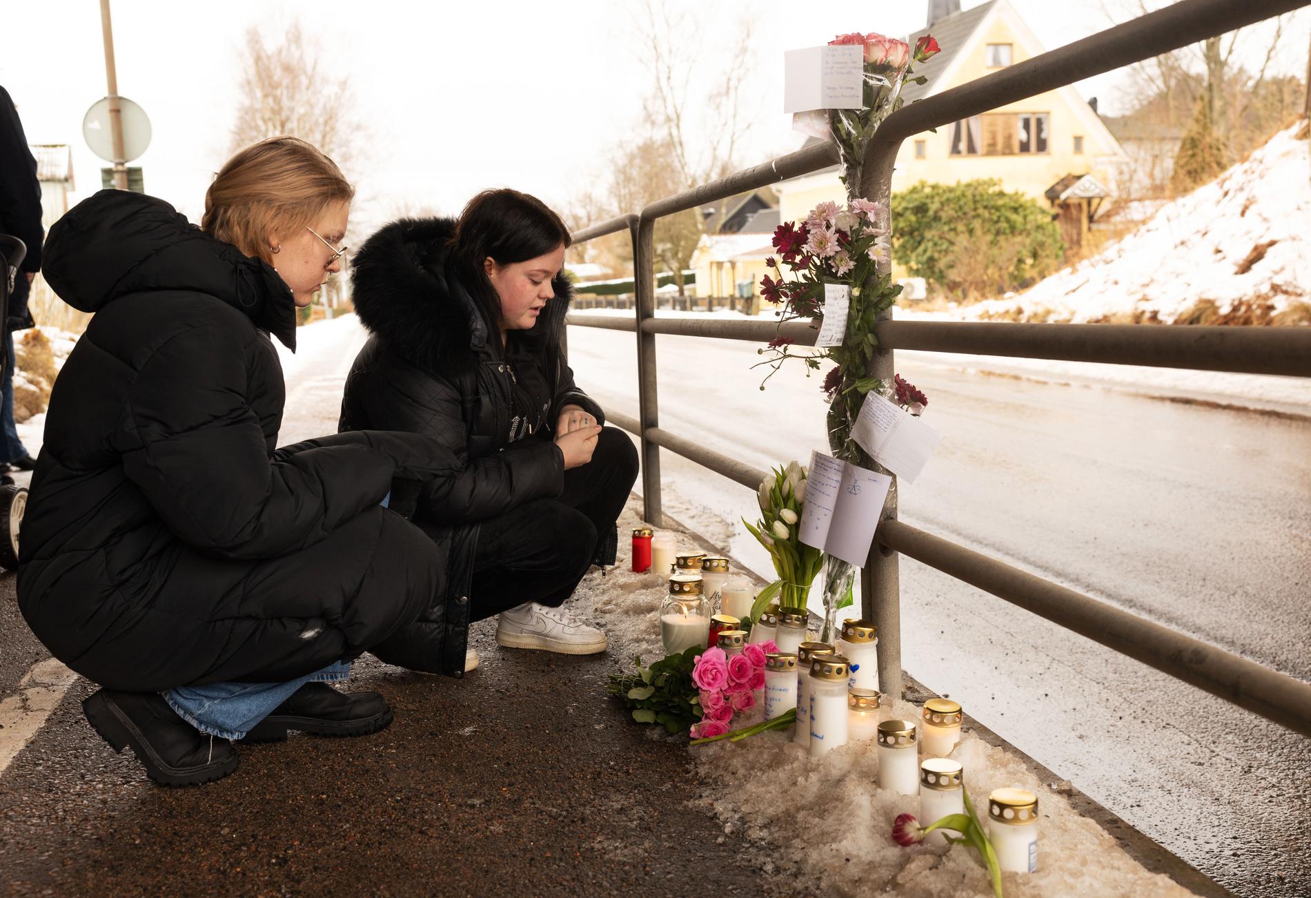 Vännerna Hanna Glanby, 22 och Patricia Nilsson, 21, sitter framför de tända ljusen och blommorna till 16-årige Jakob Halls minne.