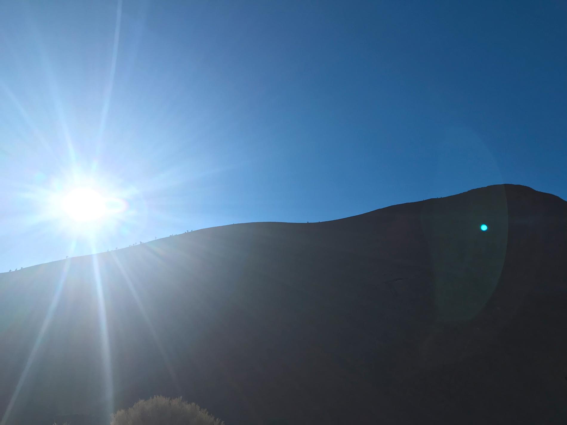 Klättrare på Uluru (Ayers Rock) avtecknar sig som små prickar längs klippans kant.