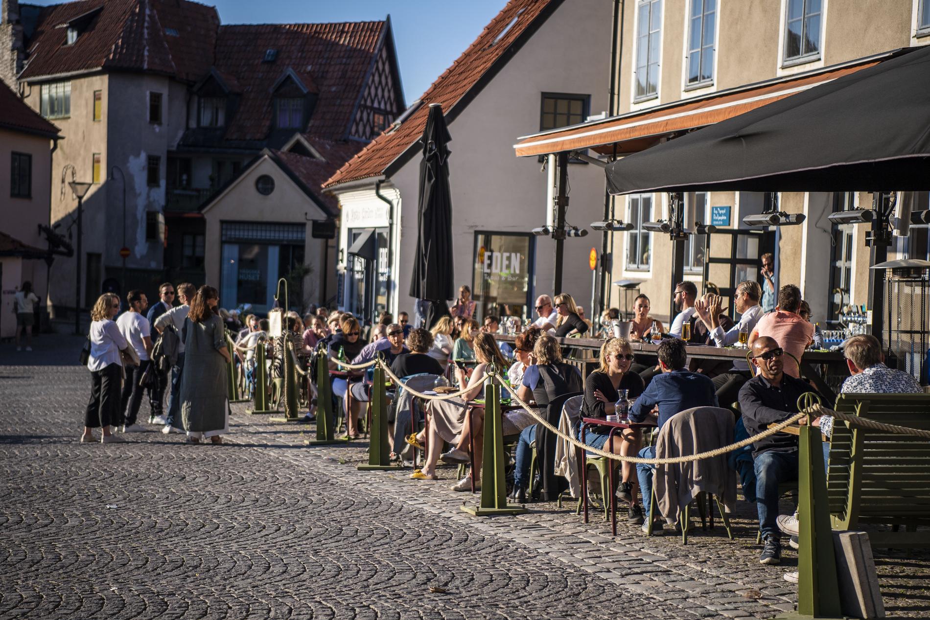 Folk njuter av solskenet på en uteservering i Visby.