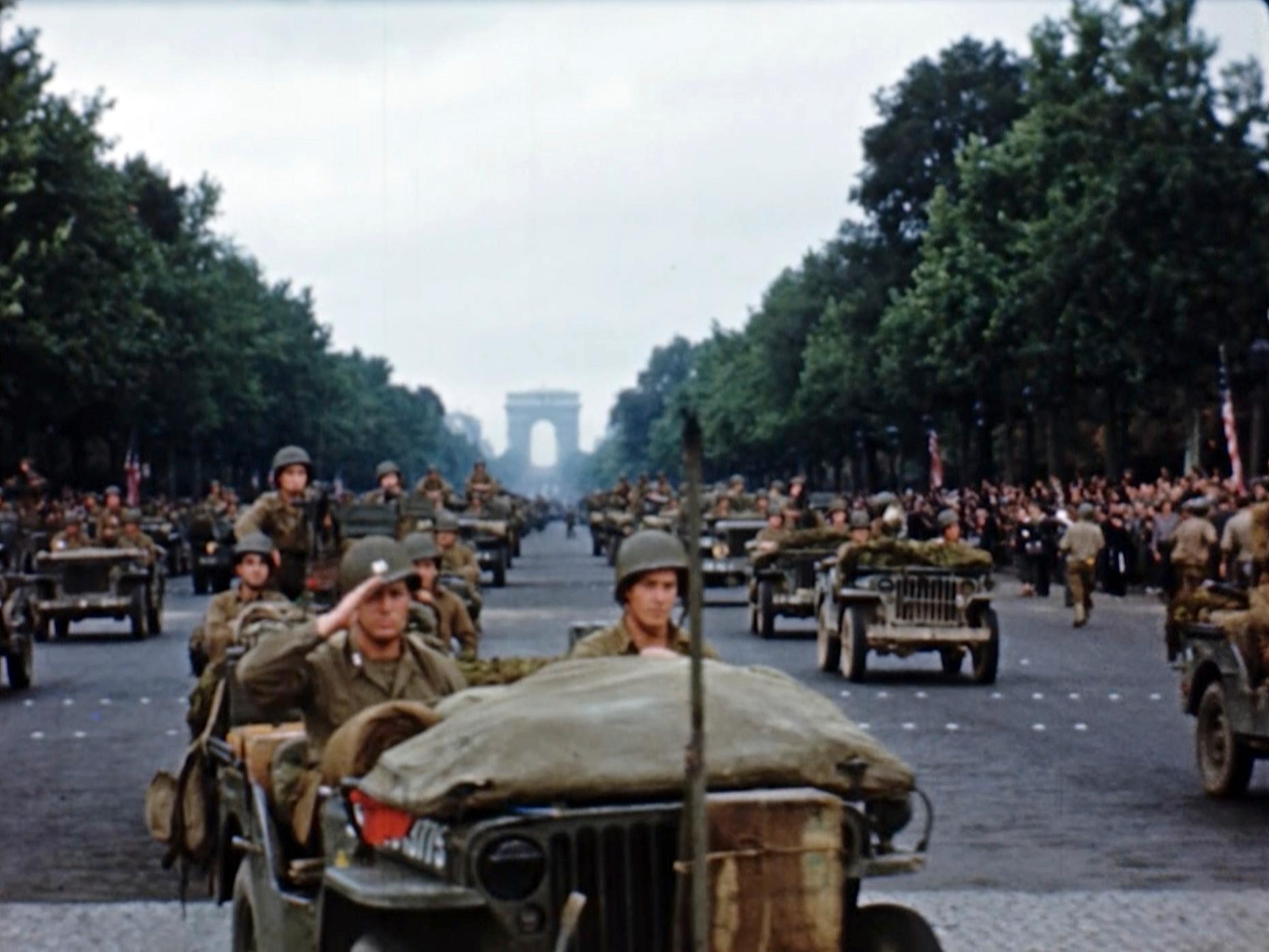 Amerikanska soldater marscherar tillsammans med stridsfordon längs Champs-Élysées efter befrielsen av Paris i augusti 1944.