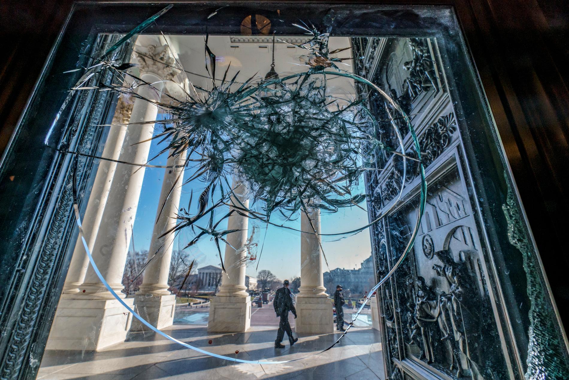 En krossad glasruta i Kapitolium påminner om förra veckans stormning.