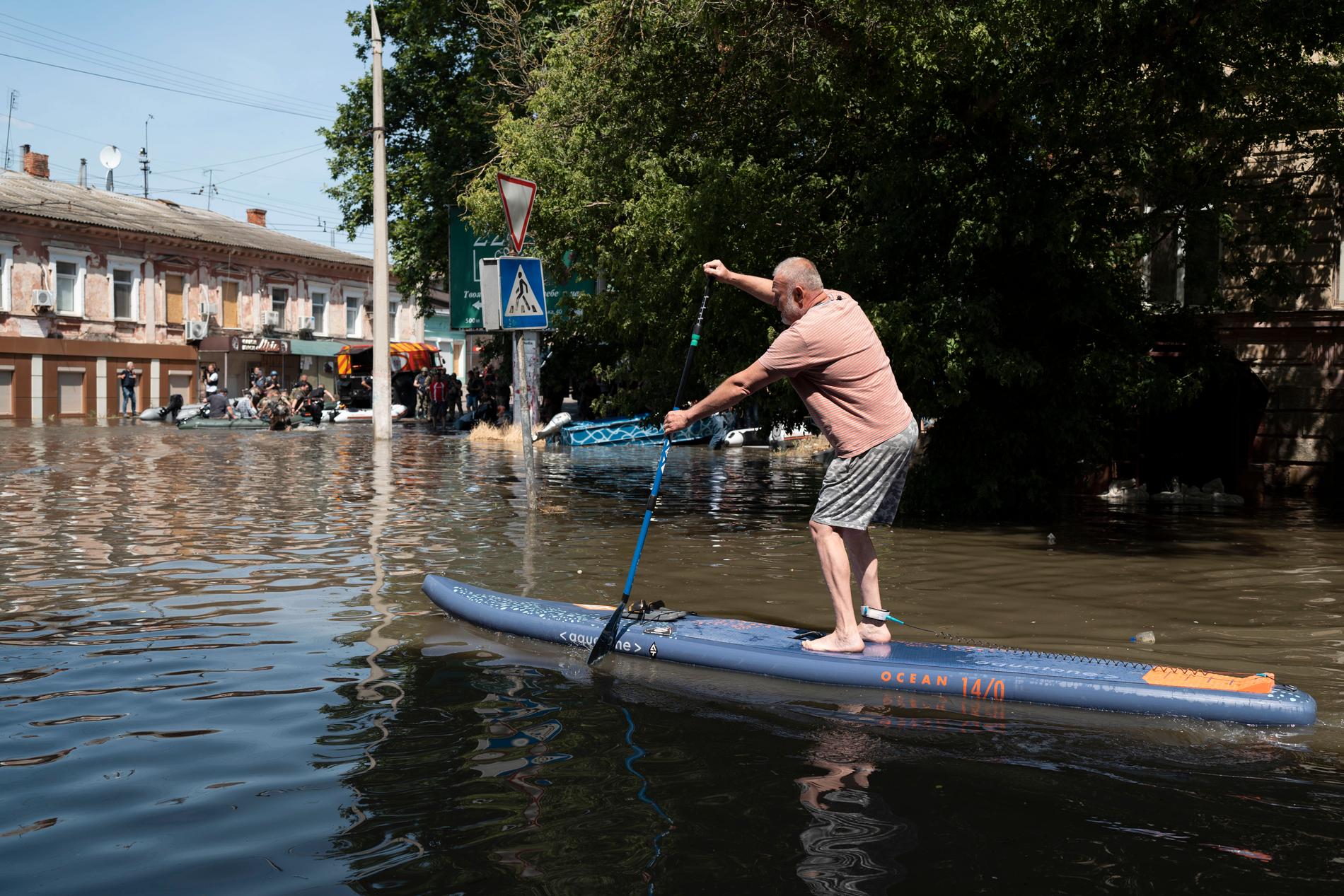 En man paddlar på de översvämmade gatorna i Cherson.