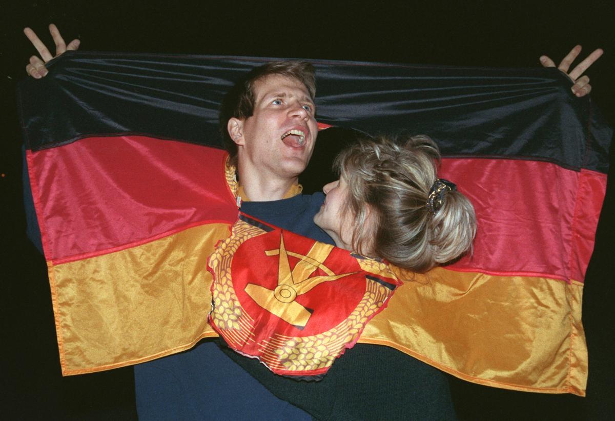 DDR-FLAGGANS SISTA DAGAR Ett par firar den tyska återföreningen i Berlin genom att drapera sig i den tidigare östtyska flaggan - här med det förhatliga DDR-emblemenet bortklippt.