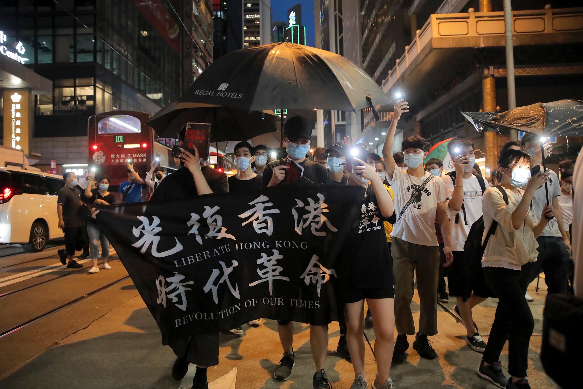 Demonstranter med en skylt med texten "Befria Hongkong, revolution i vår tid".