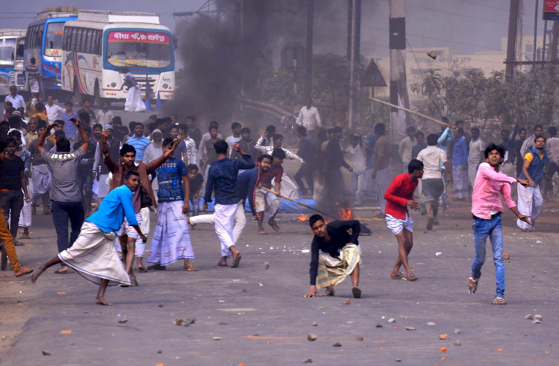 Demonstranter i utkanten av den indiska storstaden Calcutta i Västbengalen kastar sten mot polisen på lördagen.
