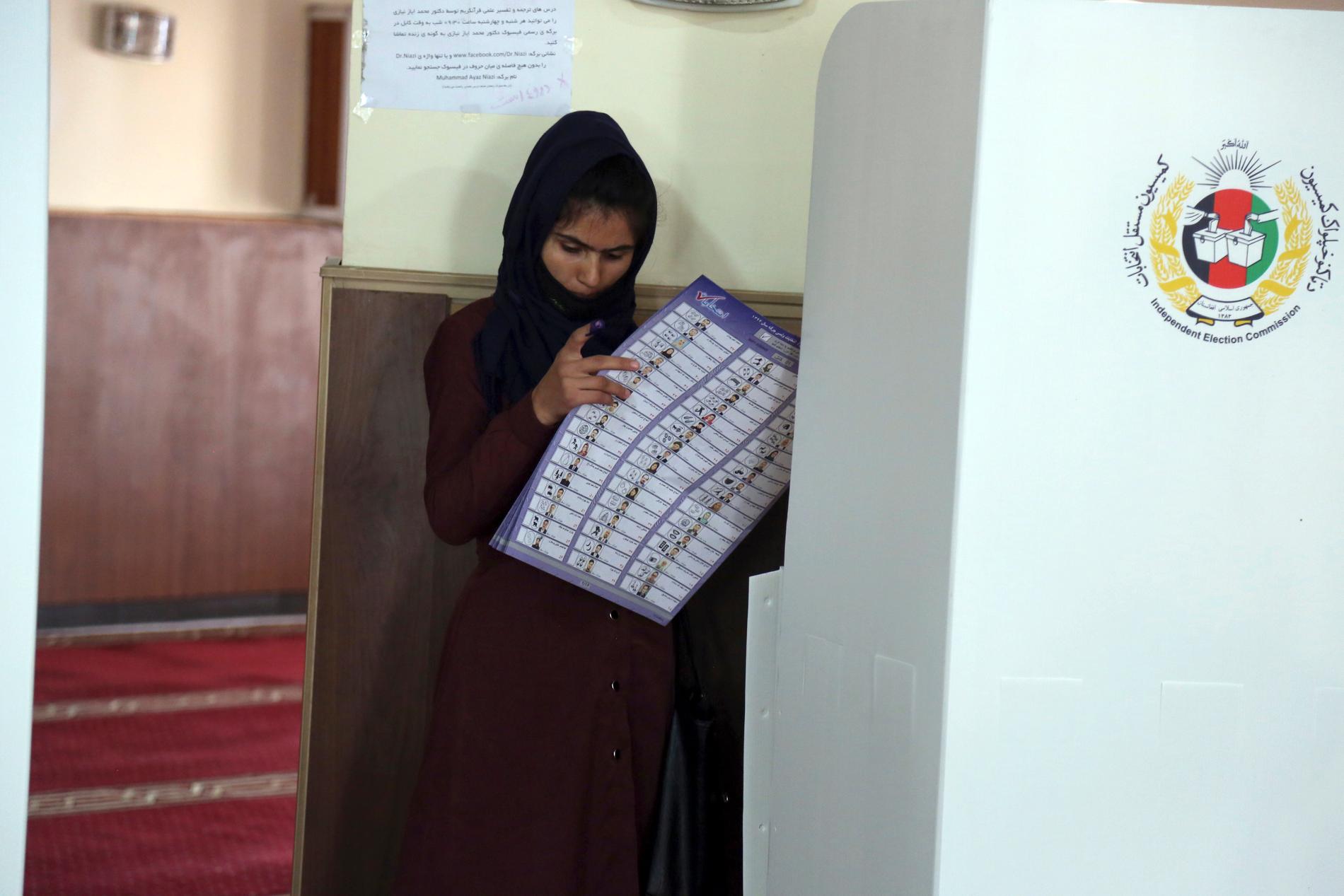 En kvinna funderar över vilken kandidat hon ska rösta på i en vallokal i Afghanistans huvudstad Kabul på lördagen.
